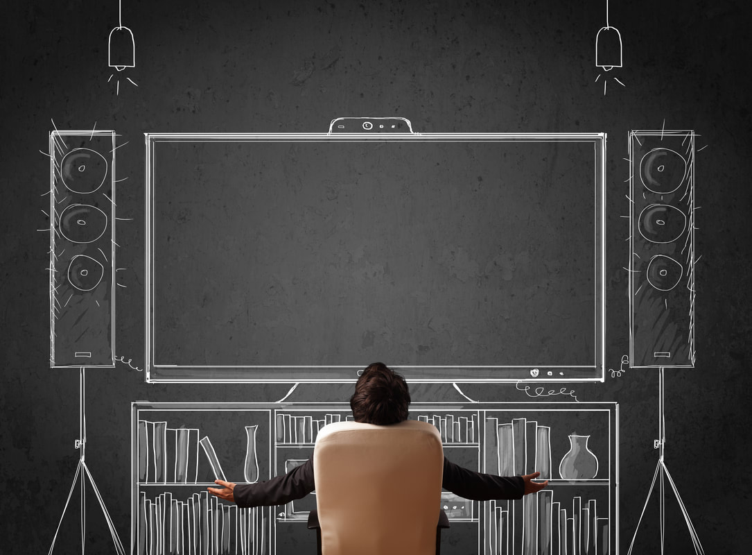man sitting in front of wall-sized chalk board drawing of a full entertainment system